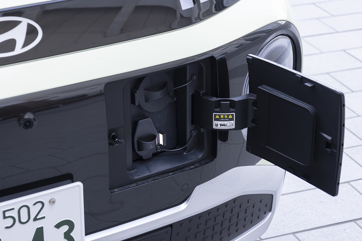 充電ポートは前のナンバープレートの隣。フタが妙に大きいのは日本のCHAdeMOにも対応したためとのこと。