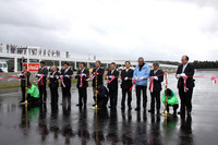 グランドスタンド前のメインストレート上で、来賓により行われたテープカット。高橋国光氏（右から5人目）、鈴木亜久里氏（左から2人目）の姿も見える。
