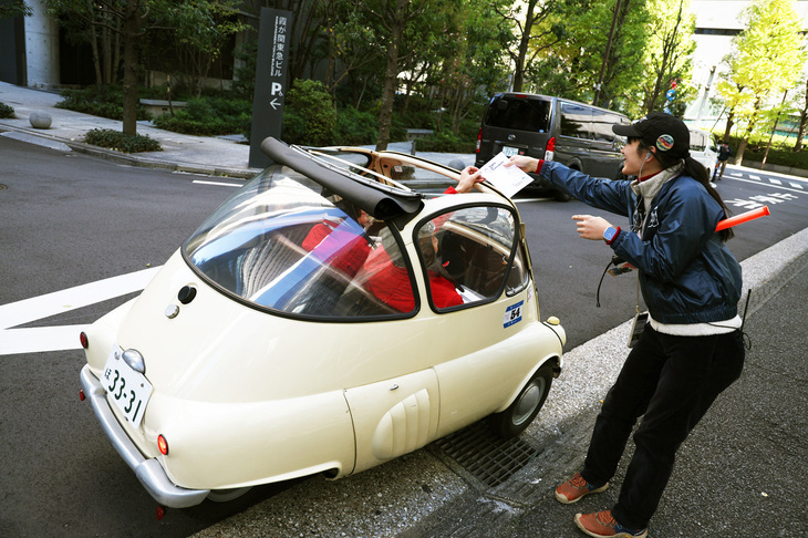 サンルーフからスタンプカードをスタッフに渡している1955年「イソ・イセッタ」。ライセンス生産された「BMWイセッタ」ではなく、イタリア製のオリジナルである。