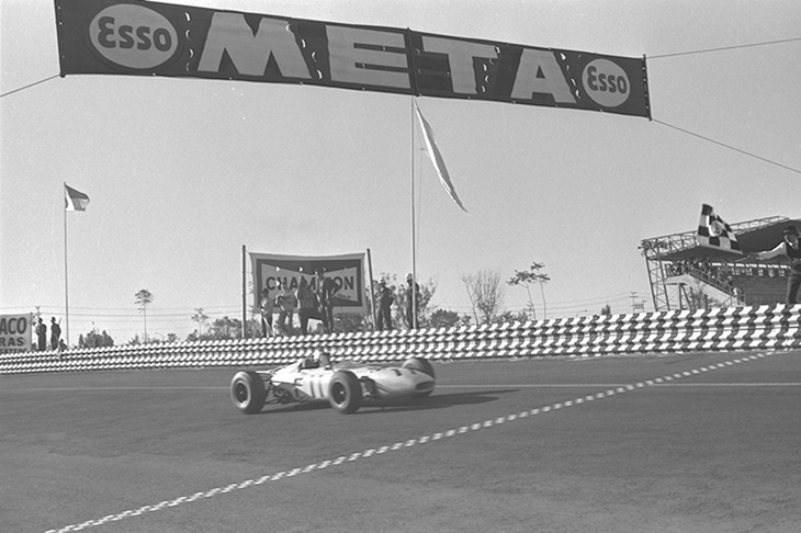 1965年のF1メキシコGPにて、1位でチェッカードフラッグを受けるリッチー・ギンサーと「ホンダRA272」。これはホンダにとってもギンサーにとっても、後にF1で黄金期を迎えるグッドイヤーにとっても初の勝利だった。