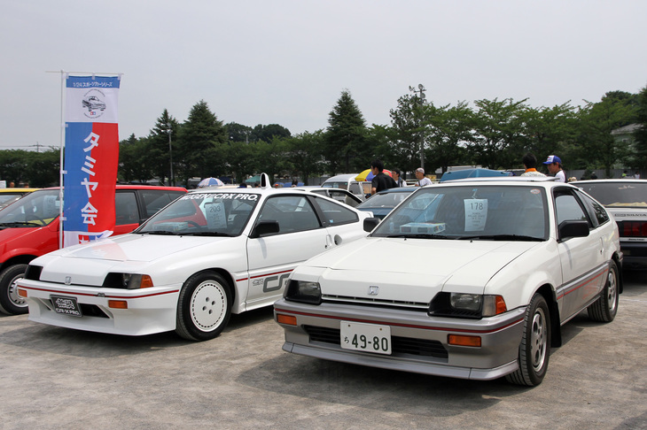 2台の「ホンダ・バラードスポーツCR-X」。右は1983年「1.5i」、左は専用のブリスターフェンダーや前後エアダムを装着した1984年「無限CR-X PRO」仕様。ノボリが立っているように、双方ともタミヤからプラモデルが（無限CR-X PROはラジコンも）リリースされていた。