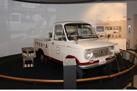 フロントサスペンションをリーフリジッドからダブルウィッシュボーンの独立式にするなど改良が施された「スズライト・キャリイL20」（1965年）。展示車両は、当時「斡旋車両」として設定されていた「アサヒビール仕様車」を再現したもの。バックのスクリーン「スズライト・キャリイ劇場」には、60年代のモノクロ写真をベースにCG（コンピュータ・グラフィクス）で制作された映像が流れる。いわばスズキ版『ALWAYS三丁目の夕日』。