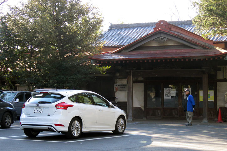 谷保天満宮の駐車場にて。奥に見える建物は参集殿。かつては結婚式などに使われていたとのことです。