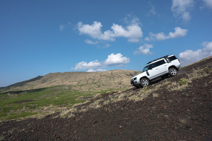 七島展望台付近のオフロードを走る「ディフェンダー130」。コースには急峻（きゅうしゅん）な上り・下り、凹凸が繰り返す波状路面、大きな落ち窪みなどがあったが、それでもディフェンダーの高いパフォーマンスを揺るがすほどではなく、試乗中はゆとりをもって雄大な景色を楽しむことができた。