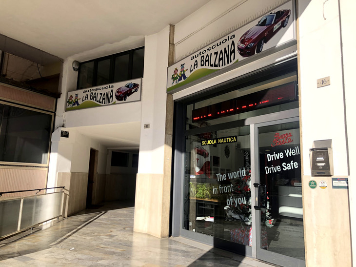 「テスラ・モデル3」を導入したバルツァナ自動車教習所。看板には、例の「フィアット124スパイダー」教習車も。