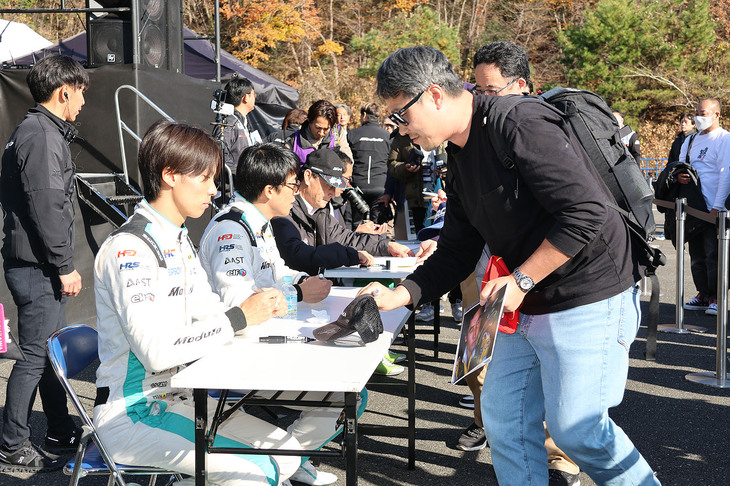 ゲストによるサイン会の様子。出席者は（写真奥から順に）土屋圭市さん、Modulo Nakajima Racingの中嶋 悟監督、伊沢拓也選手、大草りき選手という豪華メンバーで、ファンは、帽子や色紙、写真などお気に入りのアイテムにサインを求めていた。特に伊沢選手は、今シーズンを最後にSUPER GT（GT500）から引退するとあって、現役最後の貴重な機会となった。