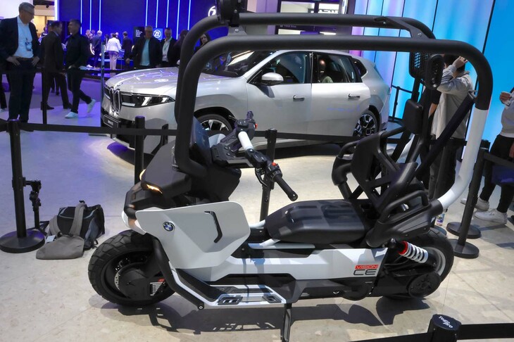 BMWモトラッドの「ビジョンCEコンセプト」（手前）。2000年代初頭に発売した「C1」のコンセプトを継承。ライダーを金属製のフレームで囲むことで、ヘルメットなどの乗員保護装備を不要とすることを目指した電気モーターサイクルで、バランシング機能も搭載している。